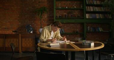A man is studying the Bible while sitting at a table indoors. He flips through the pages with a concentrated look. Daylight photo