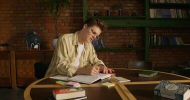 A man is studying the Bible while sitting at a table indoors. He writes in a notebook and leaves notes on stickers. Daylight photo