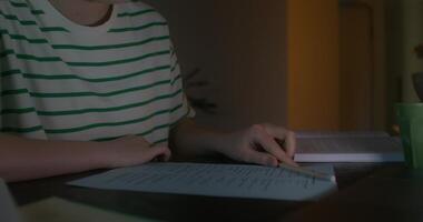 A woman uses a laptop and does a test sitting at a table in the dark. Close-up of her hands, an unrecognizable person photo