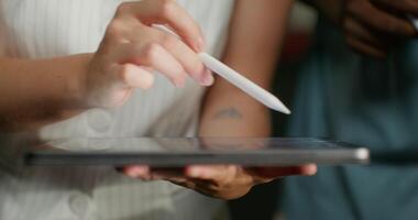 A meeting in a modern office. A woman uses a tablet while standing next to her colleagues, close-up of her hands, an unrecognizable person photo