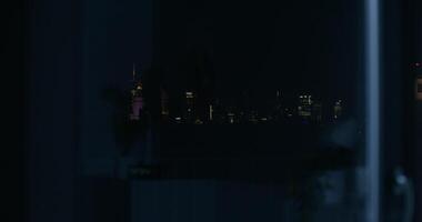View from the open window of the night city. The lights of the skyscrapers of the city center in the dark photo
