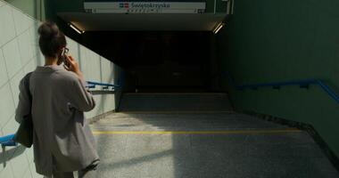 A woman in formal clothes is talking on a mobile phone going down the stairs to the subway station. Rear view, unrecognizable person photo