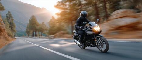 Motorcycle Rider Cruising Along a Winding Road at Sunset in Mountainous Terrain photo