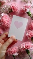 Hand Holding Card With Heart Surrounded by Pink Carnations and Gypsophila on Pastel Background photo