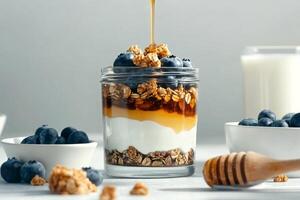 Delicious Layered Yogurt Parfait With Blueberries and Granola Drizzled With Honey for Breakfast photo