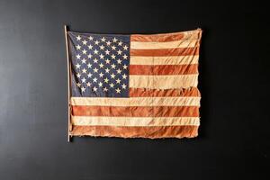 Vintage American Flag Displayed on a Dark Wall Showcasing Its Aged Texture and Design Elements photo