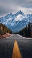 Majestic Mountain Road Under Cloudy Skies With Snow-Capped Peaks Visible in the Background photo