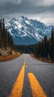 Majestic Mountain Road Under Cloudy Skies With Snow-Capped Peaks Visible in the Background. photo