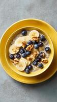 Breakfast Bowl With Sliced Bananas, Blueberries, and Walnuts Served in a Yellow Bowl. photo