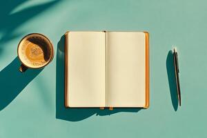 Warm Cup of Coffee With a Blank Notebook and Pen on a Teal Surface in Bright Sunlight photo