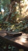 Sunlight Filtering Through Trees Highlights a Notebook on a Wooden Table in a Lush Forest. photo