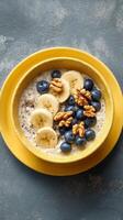 Breakfast Bowl With Sliced Bananas, Blueberries, and Walnuts Served in a Yellow Bowl photo