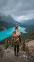 Woman Enjoying a Breathtaking View of Turquoise Lake and Mountains in National Park During Cloudy Weather. photo