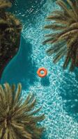 Relaxing View of a Pool Surrounded by Palm Trees With a Bright Orange Float in the Water on a Sunny Day photo