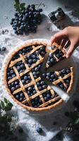 Hand Reaching for a Slice of Blueberry Pie on a Textured Surface With Fresh Berries Nearby photo