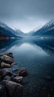 Mountain Range Reflected in Still Water Under Cloudy Sky During Early Morning in a Remote Wilderness. photo
