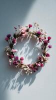 Floral Wreath Made of Dried Flowers in Soft Pink Tones Displayed Against a Light Blue Background. photo