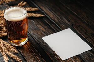 Craft Beer Served in a Glass Next to a Blank Paper on Wooden Table With Wheat photo