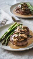 Delicious Steak With Mushroom Sauce Served With Asparagus on a Light Grey Table. photo