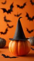 Halloween Decorations Feature a Pumpkin Wearing a Witch Hat Against an Orange Backdrop With Bats photo