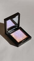 Highlighter Compact With Mirror Reflecting Soft Pastel Hues on a Neutral Background. photo