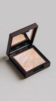 Shimmering Highlighter Compact Displayed Elegantly on a Minimalist Surface photo
