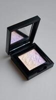 Highlighter Compact With Mirror Reflecting Soft Pastel Hues on a Neutral Background photo