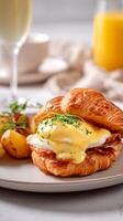 Croissant Sandwich With Eggs, Hollandaise Sauce, and a Side of Roasted Potatoes and Fruit photo