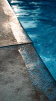 Water Glistens Under Sunlight Near the Edge of a Swimming Pool With Textured Concrete Surface photo