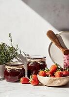 Homemade Strawberry Jam Jars Next to Fresh Strawberries in a Kitchen Setting photo
