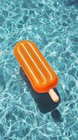 Bright Orange Popsicle Float Drifts in a Sparkling Swimming Pool on a Sunny Day photo