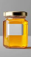 Natural Honey in a Clear Glass Jar With a Gold Lid Displayed on a Gray Background photo