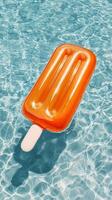 Bright Orange Popsicle Float Drifts in a Sparkling Swimming Pool on a Sunny Day. photo