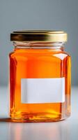Bright Orange Honey in a Glass Jar With a Gold Lid Against a Simple Background photo