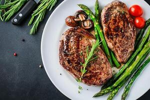 Succulent Grilled Steak Served With Fresh Asparagus and Mushrooms on a Rustic Wooden Table. photo