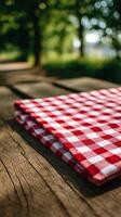 Red and White Checkered Picnic Cloth on Wooden Table in a Lush Outdoor Setting During Daylight Hours photo