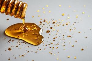 Golden Honey Drizzling From a Honey Dipper on a Gray Surface With Sparkling Droplets photo