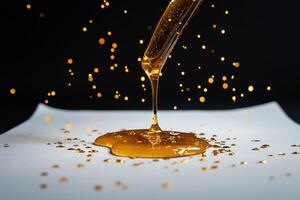 Golden Honey Drizzling From a Honey Dipper on a Gray Surface With Sparkling Droplets. photo