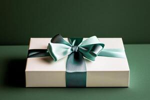 Elegant Gift Box Wrapped With Teal Ribbon Against a Green Background photo