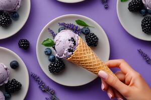 Hand Holding Lavender Ice Cream Cone With Berries on Plates and Purple Background photo