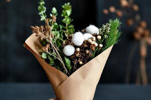 Unique Bouquet of Dried Flowers and Greenery Held in a Hand Surrounded by Natural Background. photo