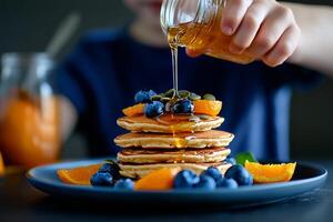 Stack of Pancakes Topped With Blueberries and Honey Drizzled in a Warm Kitchen Setting. photo