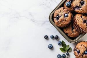 Freshly Baked Blueberry Muffins Arranged in a Metal Tray With Fresh Blueberries Scattered Around photo