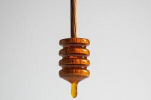 Honey Drips Slowly From a Wooden Dipper Against a Light Background photo