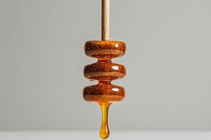 Honey Dripper With Golden Honey Droplet Against a Simple Background in a Kitchen Setting photo