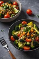 Two bowls of broccoli and tomatoes with a fork photo