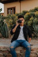 Man taking a photo with a camera in front of a house