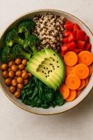 A bowl filled with vegetables, carrots, and avocado photo