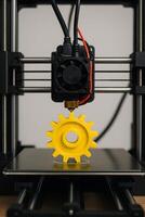 A 3d printer with a yellow gear on top photo
