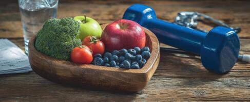 The vibrant wooden bowl filled with fresh fruits and vegetables beside a dumbbell. photo